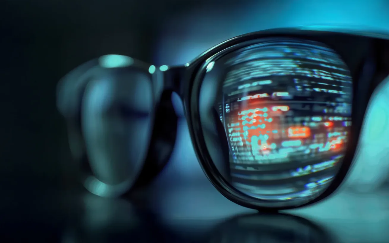Glasses resting on a table with a data reflection visible in one lens.