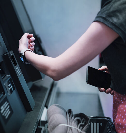 A woman using a smart watch to make a payment on a payment terminal.