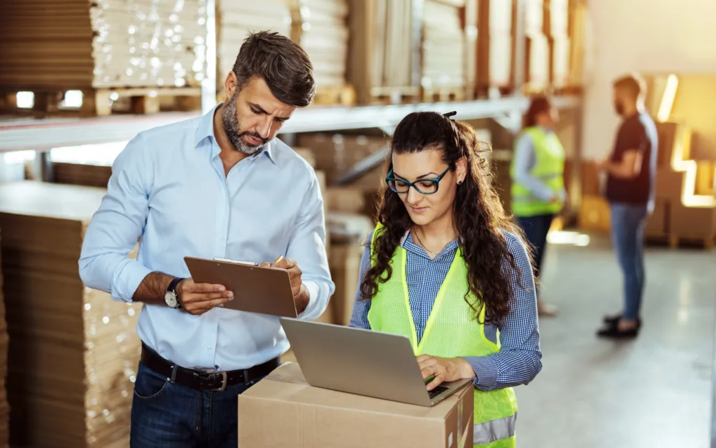 Warehouse staff looking at laptop while working.