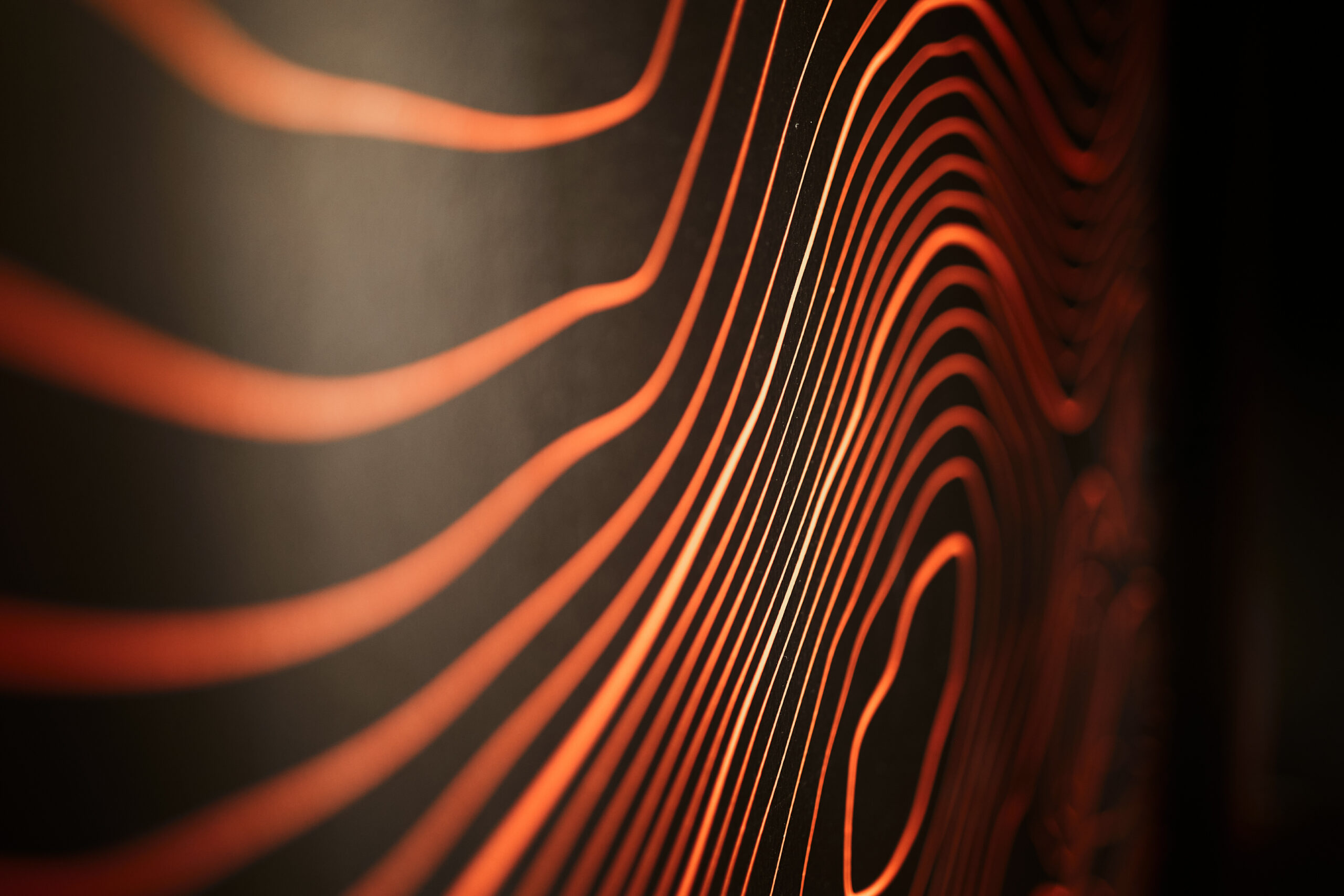 Bild von orangen Linien, die sich über eine schwarze Oberfläche schlängeln.