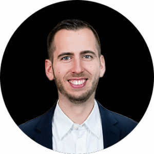 Ein Mann in dunkler Anzugsjacke und weißem Hemd lächelt vor einem schwarzen, runden Hintergrund in die Kamera und repräsentiert die valantic dmexco auf der dmexco2025.