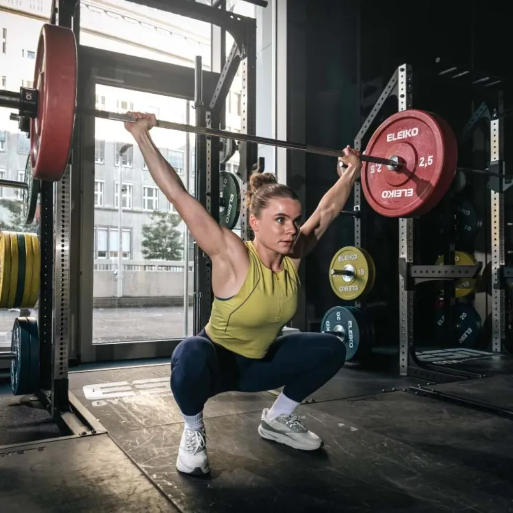 Junge Frau beim Gewichtheben im Sportstudio, toptit dank der Produkte von The Quality Group (TQG). TQG steigert die eigene Performance mit SAP Cloud ERP