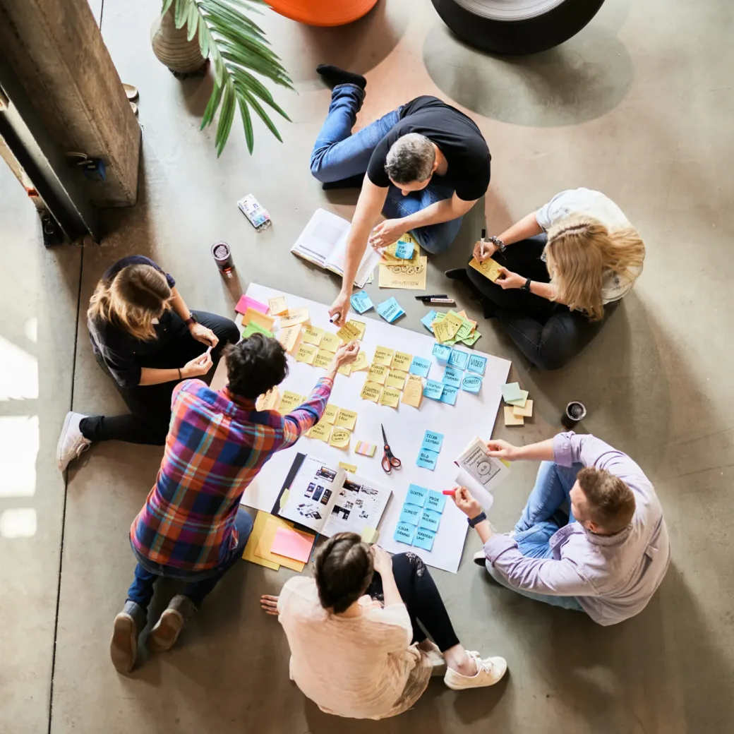 valantic Mitarbeiter:innen sitzen auf dem Boden und arbeiten an einem Projekt