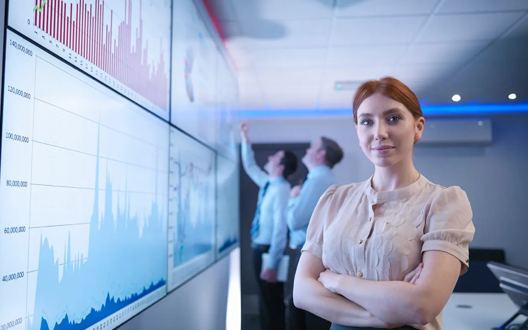 Frau im Büro, Projektion auf Whiteboard, zwei Männer diskutieren davor, kühle Blautöne.