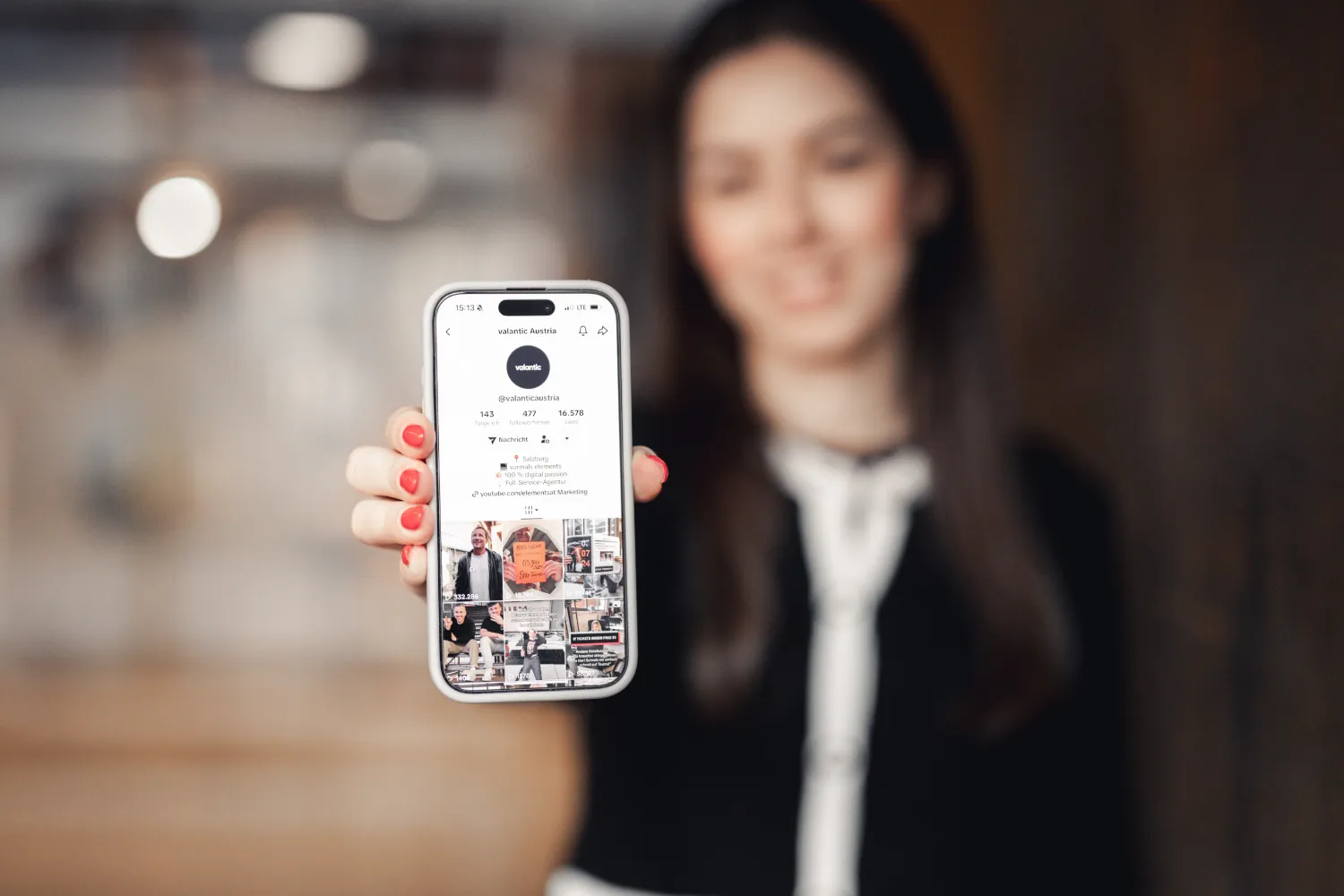 Eine Frau hält ein Smartphone in der Hand, auf dem eine Instagram-Profilseite zu sehen ist, die die Macht des Creative Testing demonstriert, wobei der Bildschirm klar fokussiert ist und die Frau im Hintergrund unscharf ist.