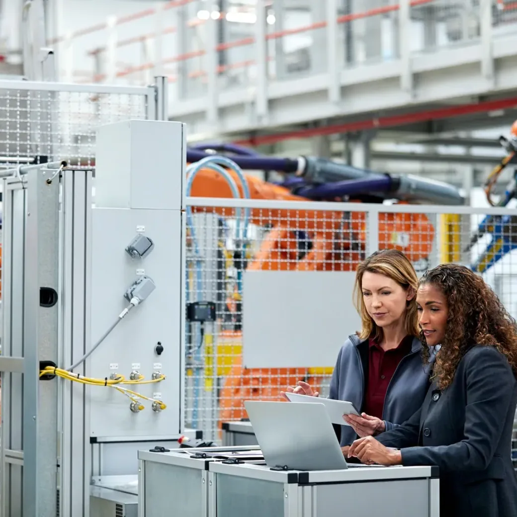 Zwei Frauen in einer Produktionsstätte, die auf einen Laptop schauen, valantic SAP Digital Manufacturing Solutions