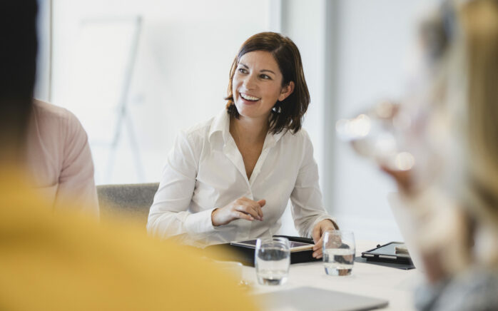 Lächelnde Geschäftsfrau in einem Meeting | Visana Success Story über MicroStrategy zur Produktivitätssteigerung des Vertriebs | RISE with SAP