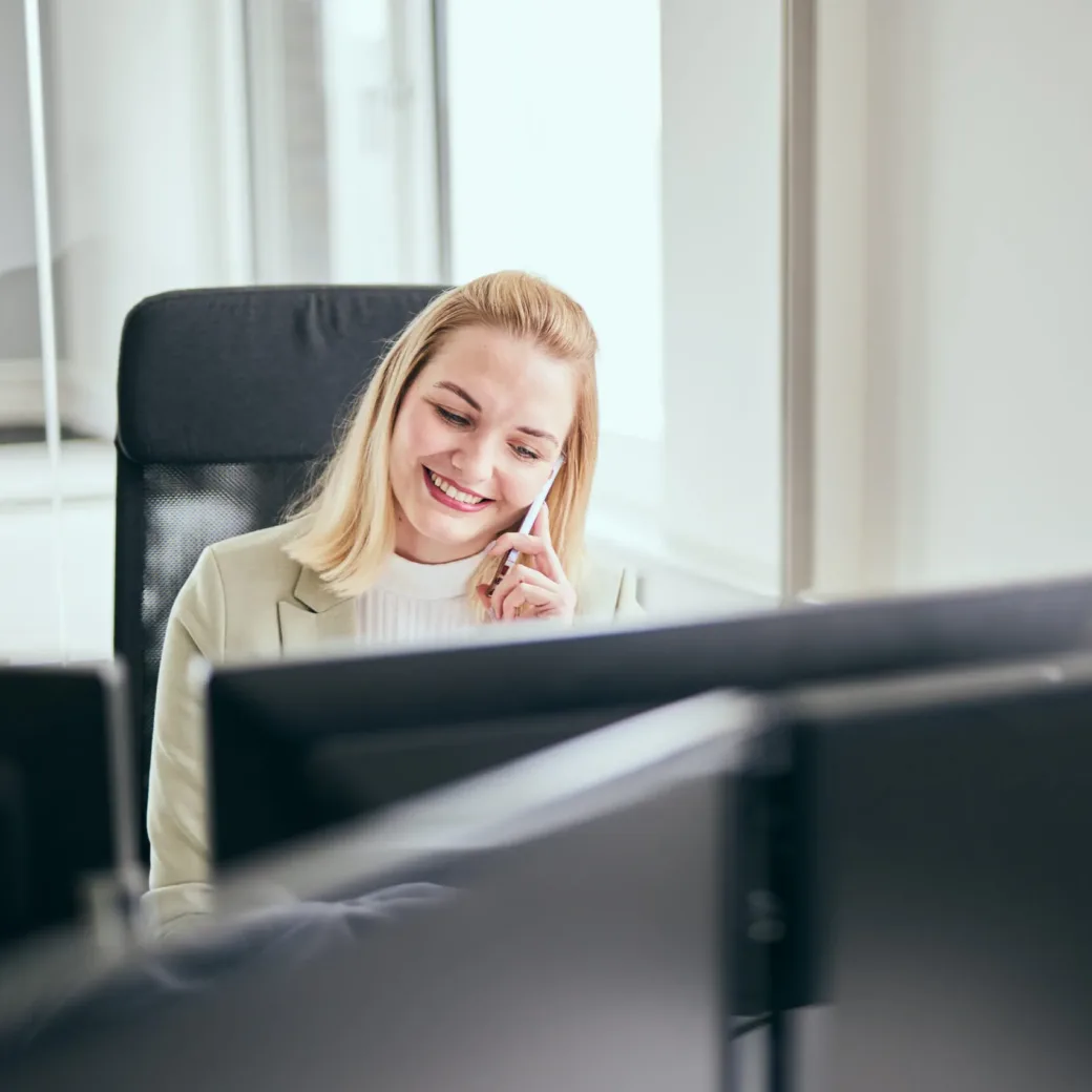 Photo of a valantic CX employee talking to a customer on the phone at her desk.