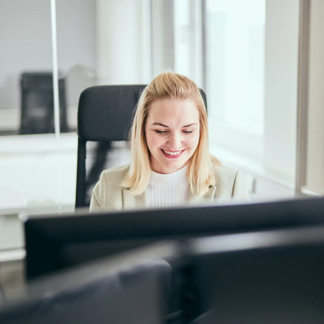 Photo of young woman smiling looking at her computer screen.