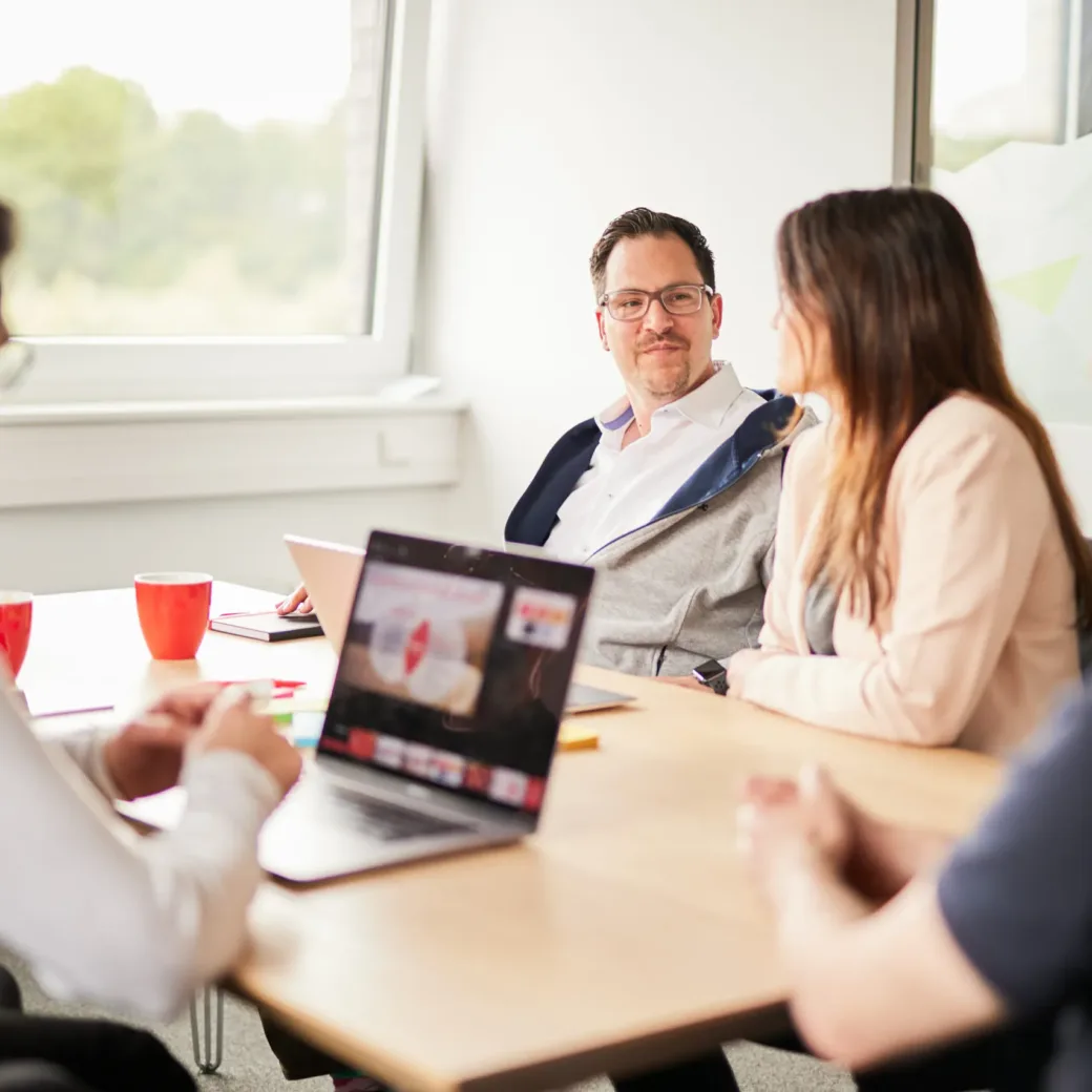 Foto von einem kleinen Team bestehend aus fünf Personen während eines Meetings.