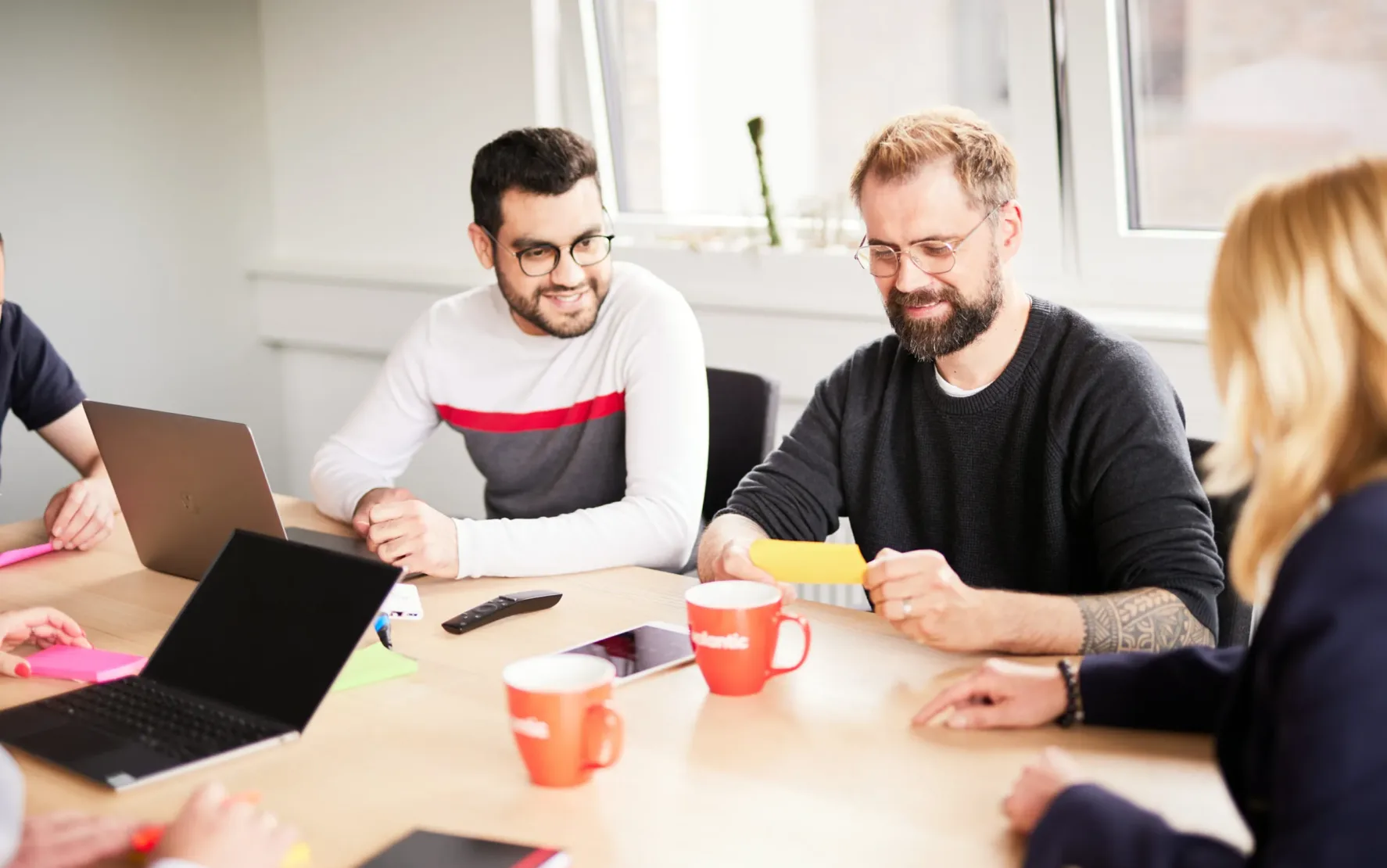 Photo of a valantic CX meeting where a man reads something from a post-it to his colleagues.