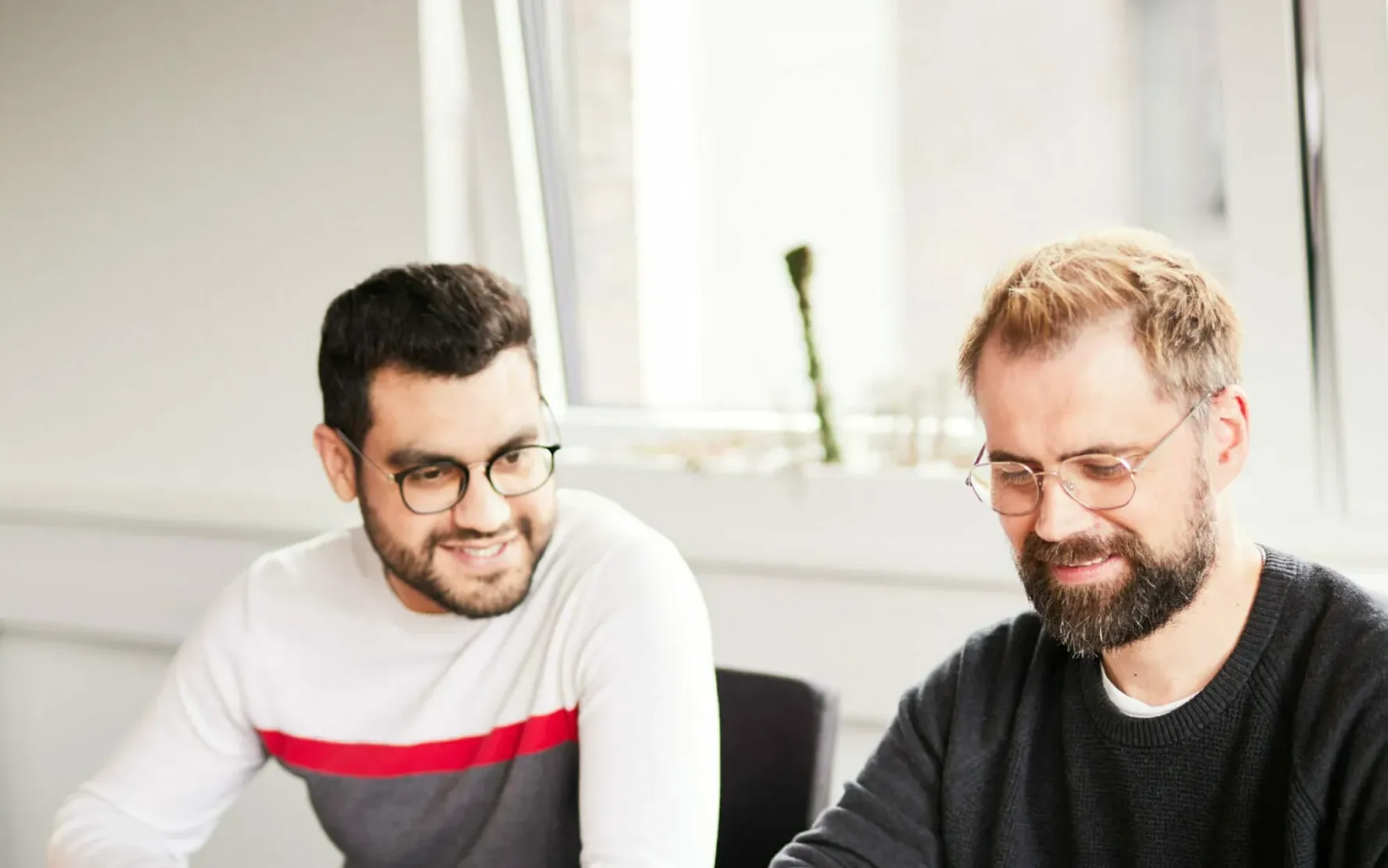 Foto von einem valantic-CX-Meeting, in dem ein Mann seinen Kolleg*innen etwas von einem Post-it vorliest.