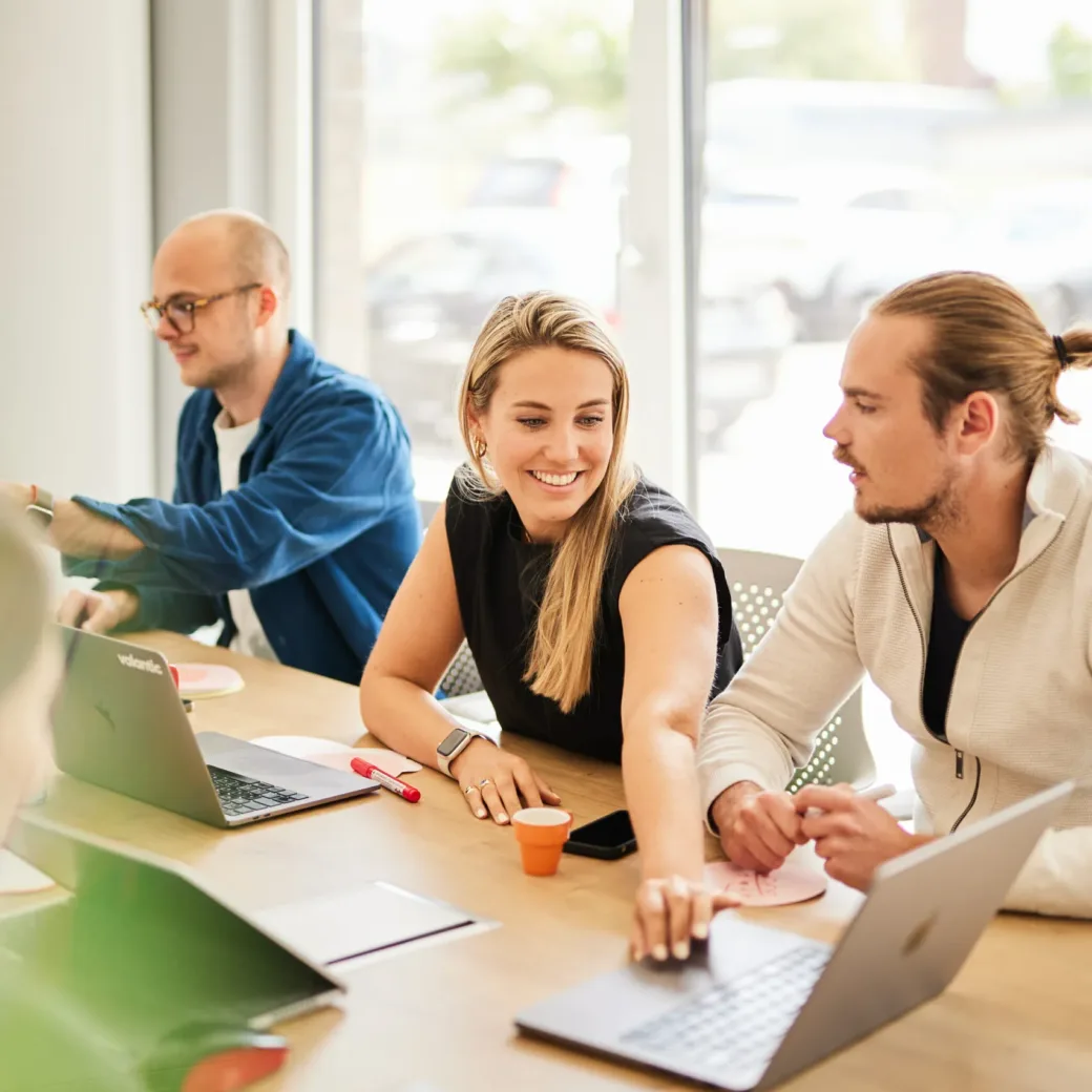 Photo of a smiling woman reaching for a laptop on the conference table, just before a valantic CX meeting.