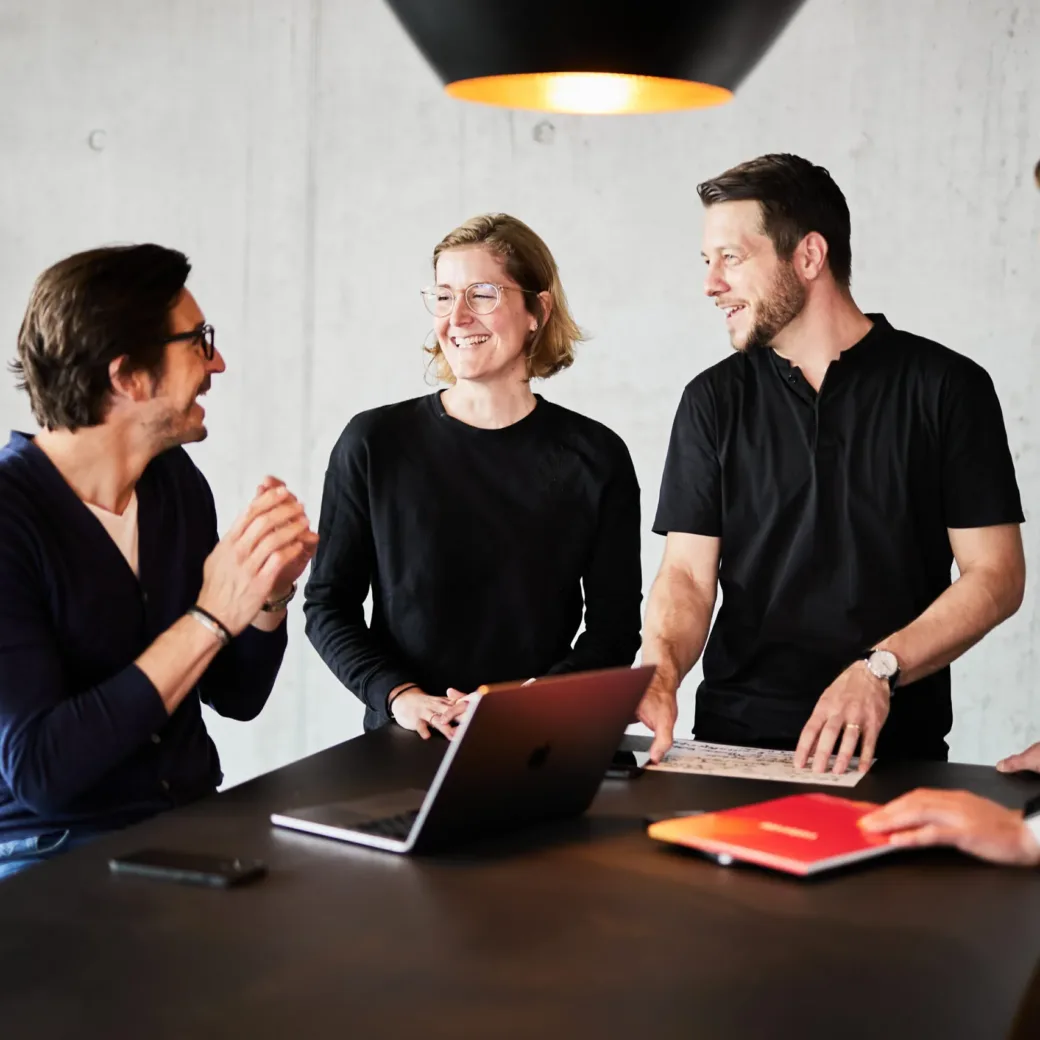 Four colleagues having a meeting at a standing desk.