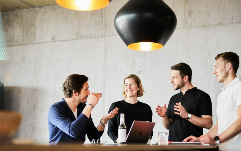 Foto von einem Teammeeting am Stehtisch.