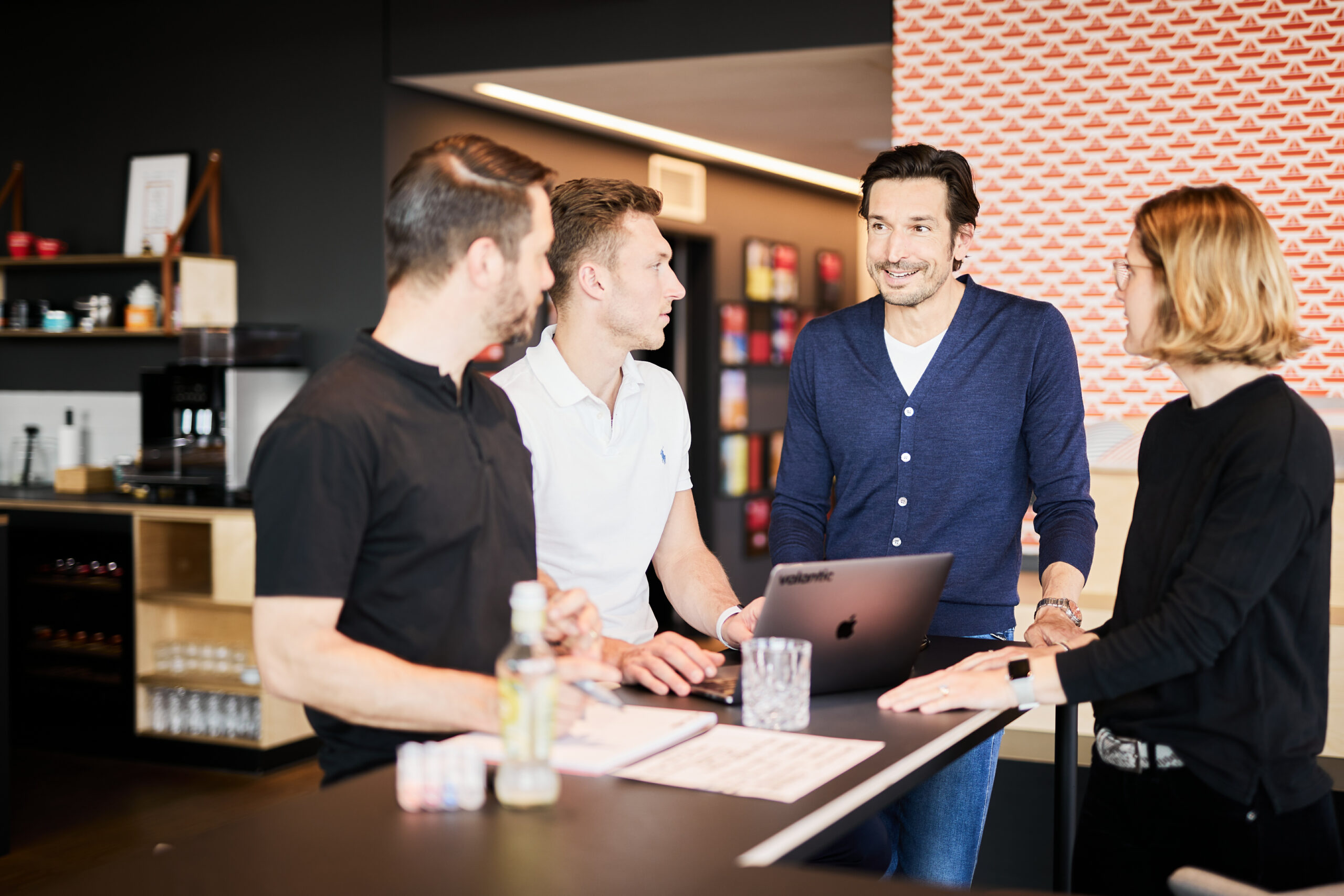 Photo of three colleagues having a meeting at a standing desk.