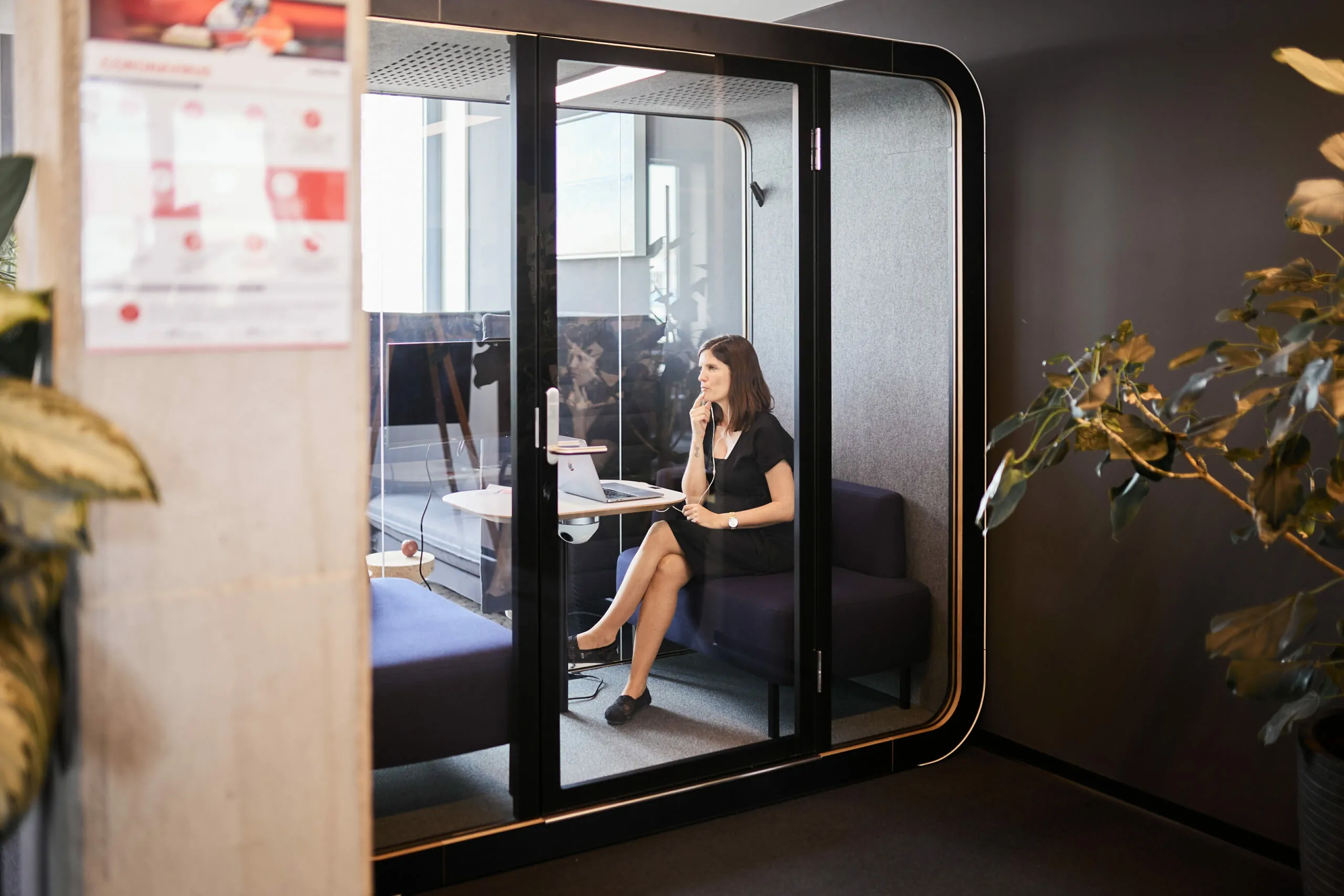 Foto von einer valantic-CX-Angestellten, die in einer Büro-Telefonzelle ein Telefonat über Customer Experience führt.
