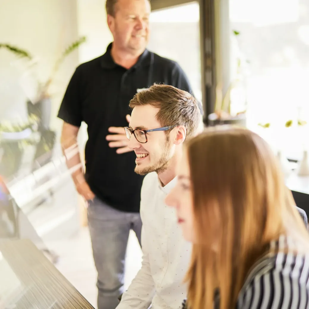 Photo of three people in a meeting in a light-filled meeting room.