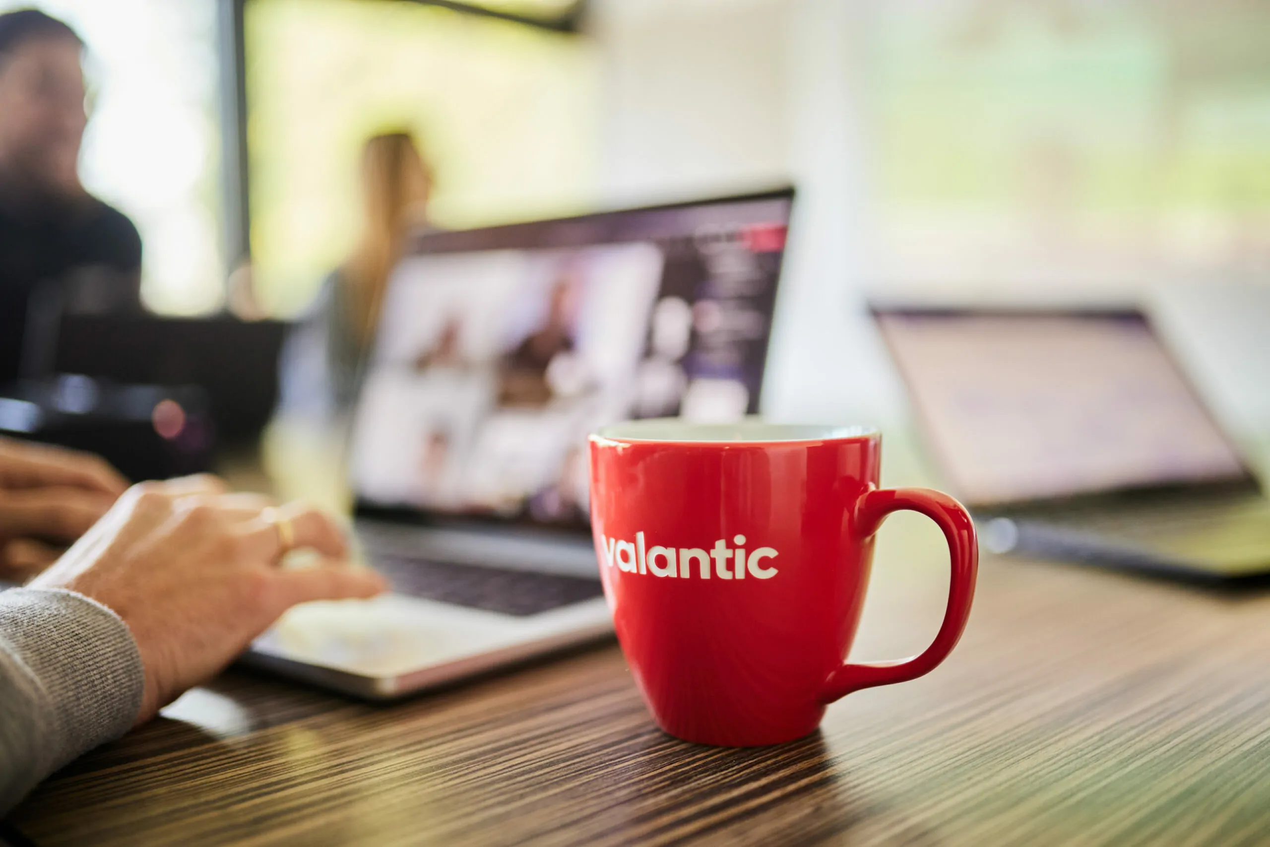 Close-up of a valantic cup standing in front of a laptop where someone is optimizing a customer journey.