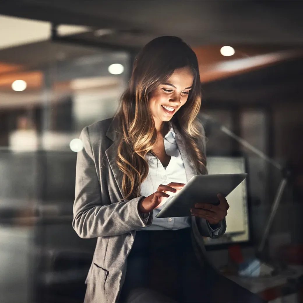 Cropped shot of a young attractive businesswoman using a tablet while working late at night in the office