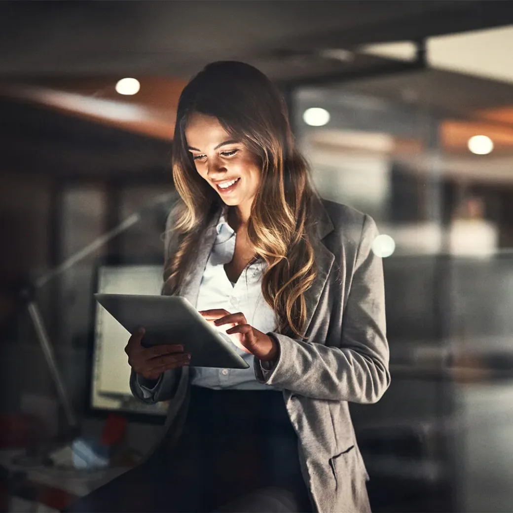 Cropped shot of a young attractive businesswoman using a tablet while working late at night in the office