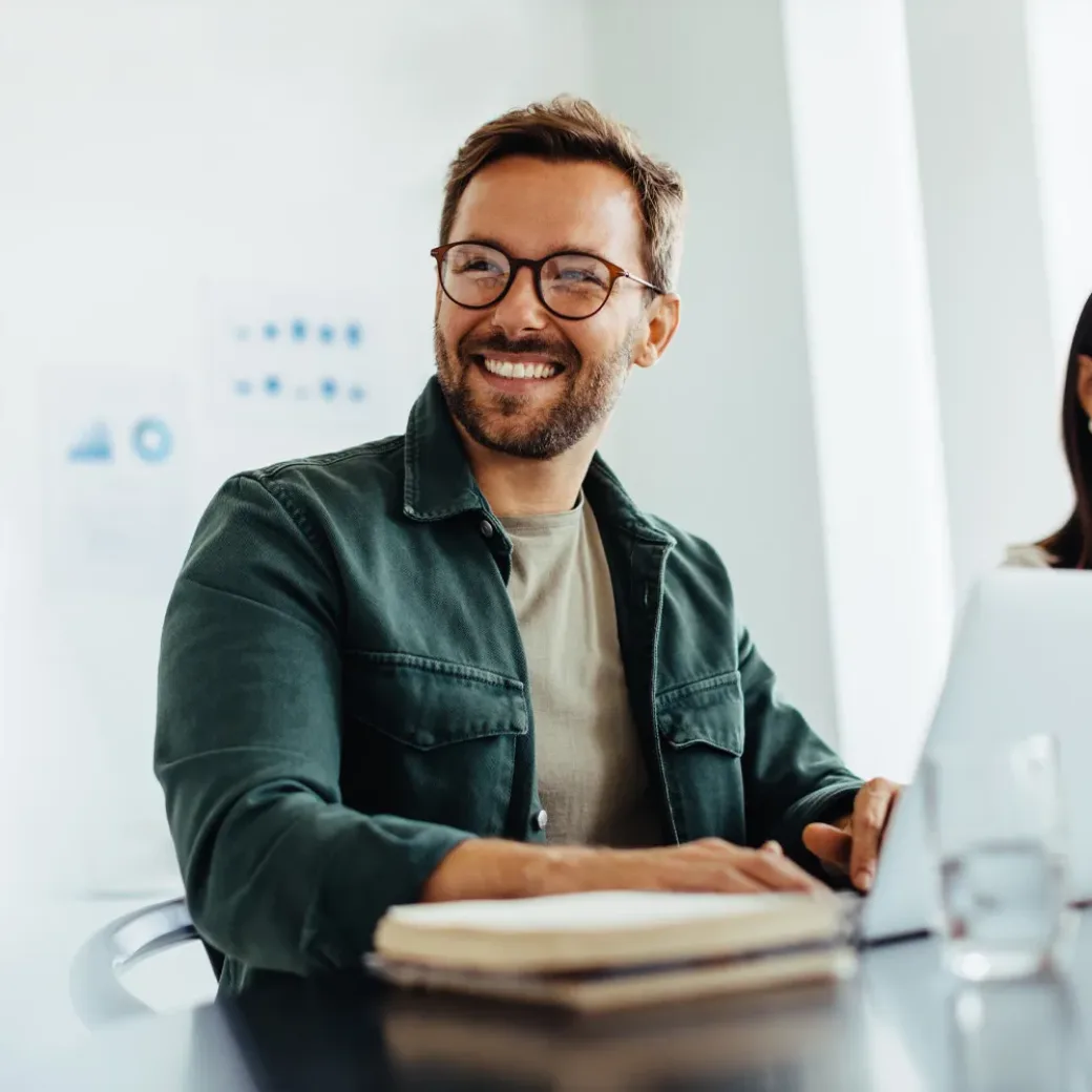 Happy business man listening to a discussion in an office boardroom. Business professional sitting in a meeting with his colleagues.