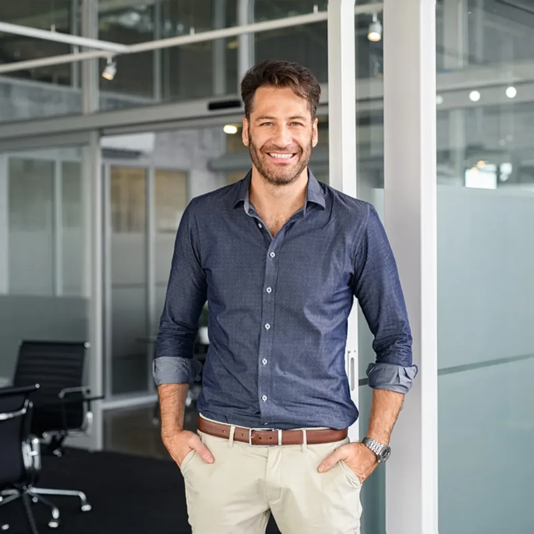 Portrait of a man with hands in pocket standing in an office while looking at camera.