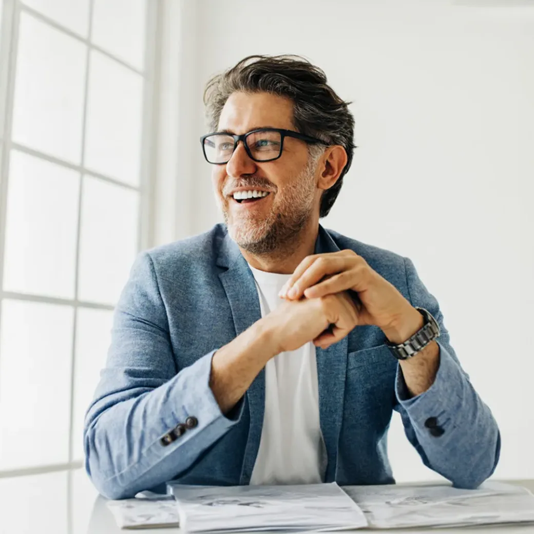 Business man looking outside the window in an office. Senior business man thinking about work while sitting at his desk in a suit.