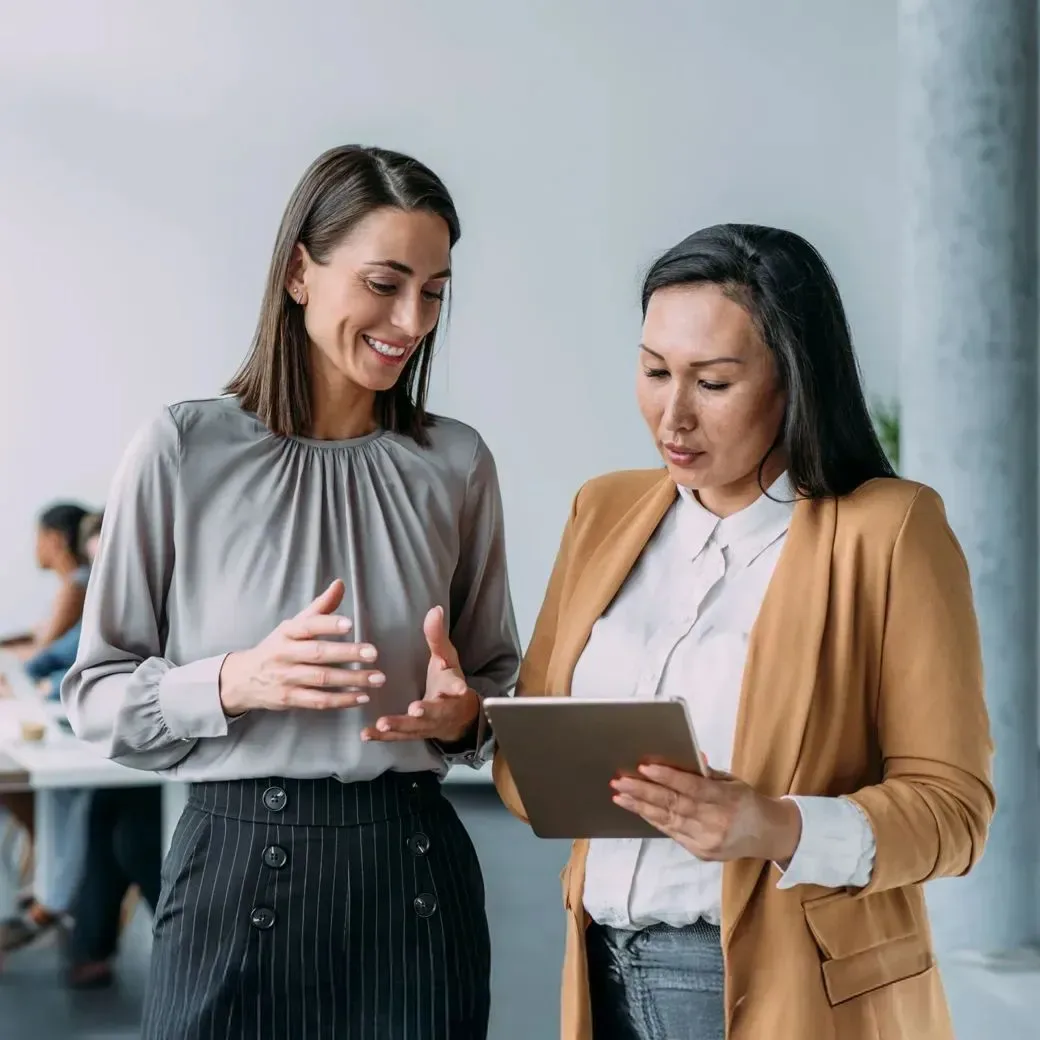 Zwei Businessfrauen diskutieren in einem Büro über geschäftliche Angelegenheiten.