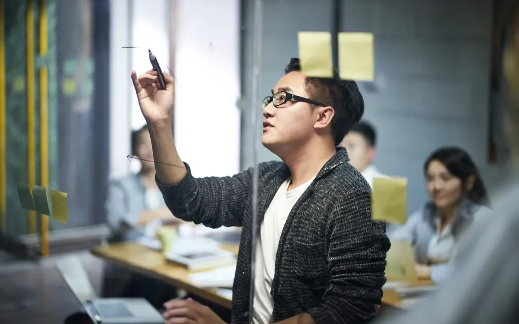 Business man drawing a diagram on glass during meeting in office.