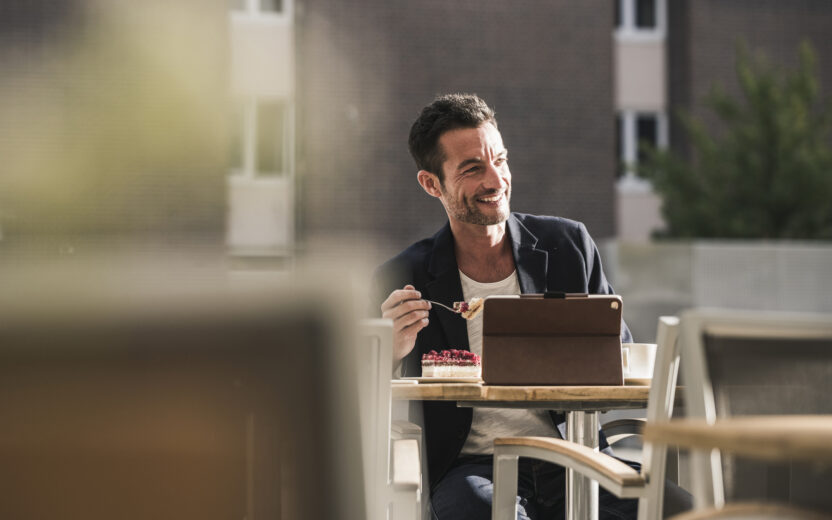Businessman sitting in cafe, drinking coffee, using smartphone