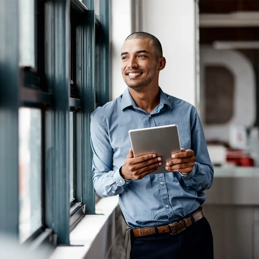 Shot of a young businessman using a digital tablet while standing at a window in an office