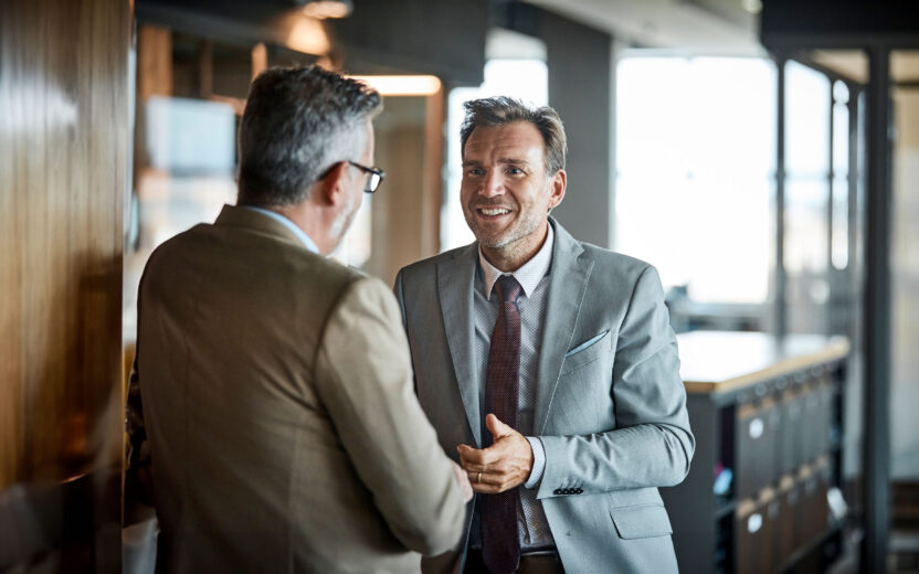Senior businessman smiling while looking at colleague