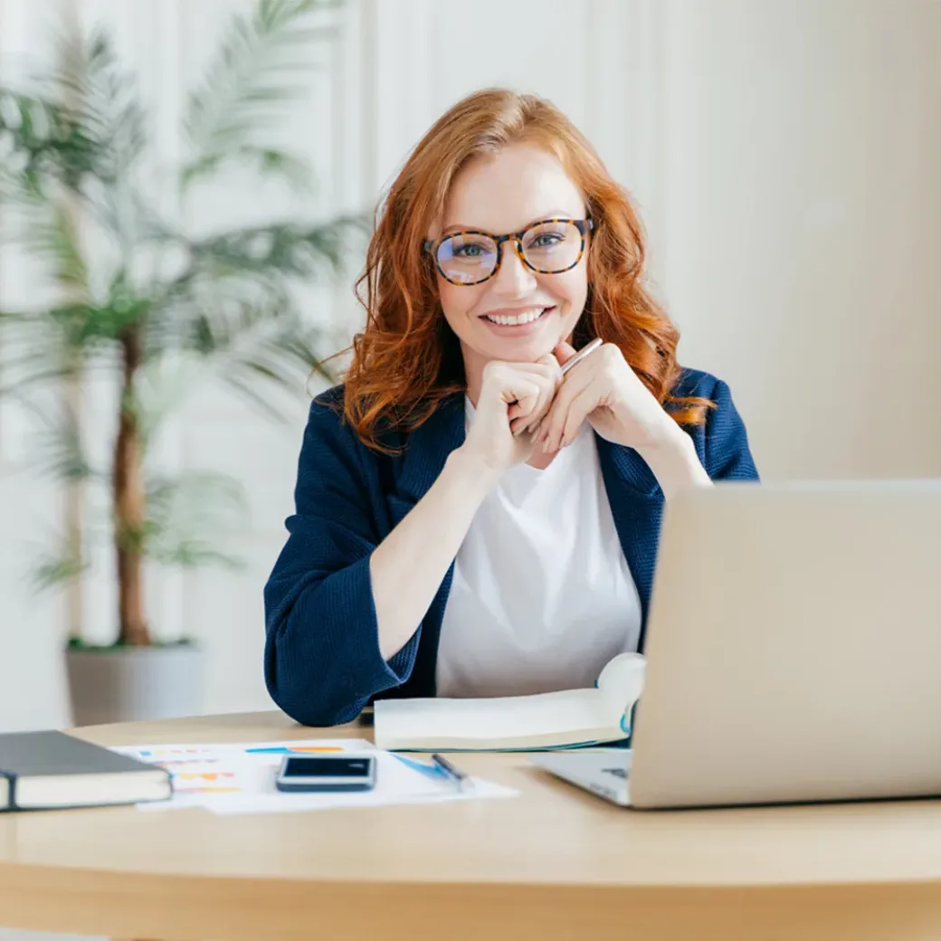 Smiling business woman sitting in front of Laptop