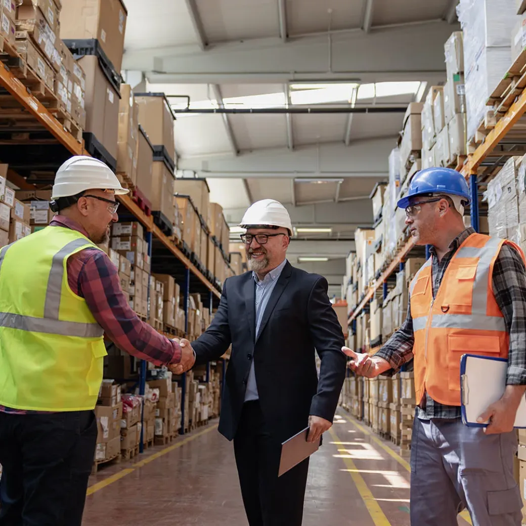 Efficient Collaboration in an Industrial Factory Warehouse: Businessman Engaging with Worker and Engineer, Exchanging Handshake