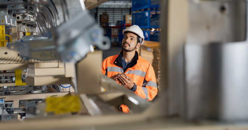 Young man industrial engineer wearing a white helmet while check the welding on the production line in the factory.