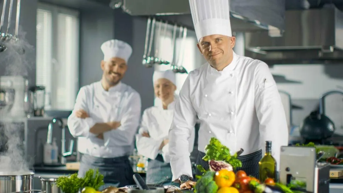 Três cozinheiros sorridentes numa cozinha junto de vegetais, caso de sucesso Burgis, Introdução ao SAP Analytics Cloud