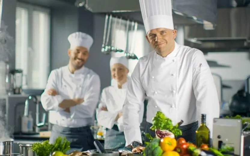 Três cozinheiros sorridentes numa cozinha junto de vegetais, caso de sucesso Burgis, Introdução ao SAP Analytics Cloud