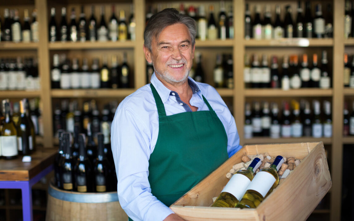 Bild von einem lächelnden Mann, der eine Weinkiste in der Hand hält | Erfolg im Handel dank Omnichannel Integration