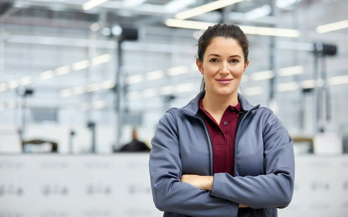Picture of a female engineer with folded arms in car factory | PlastiVation Plans and Designs Product Lifecycle Management (PLM) With valantic’s Help