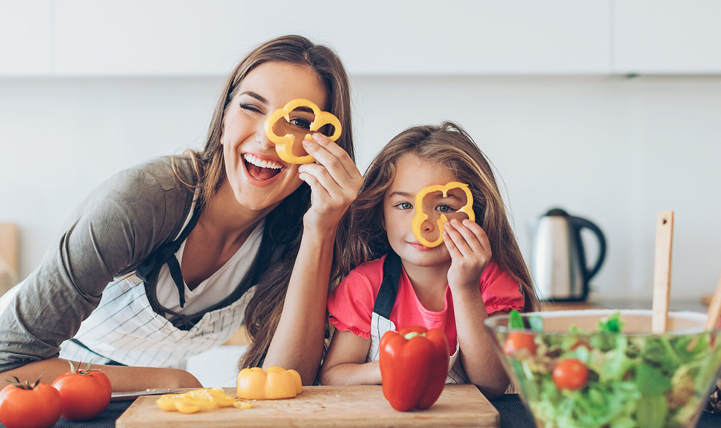 Bild von einer glücklichen Mutter mit Tochter die durch eine aufgeschnittene Paprika schauen, Omnichannel Plattform