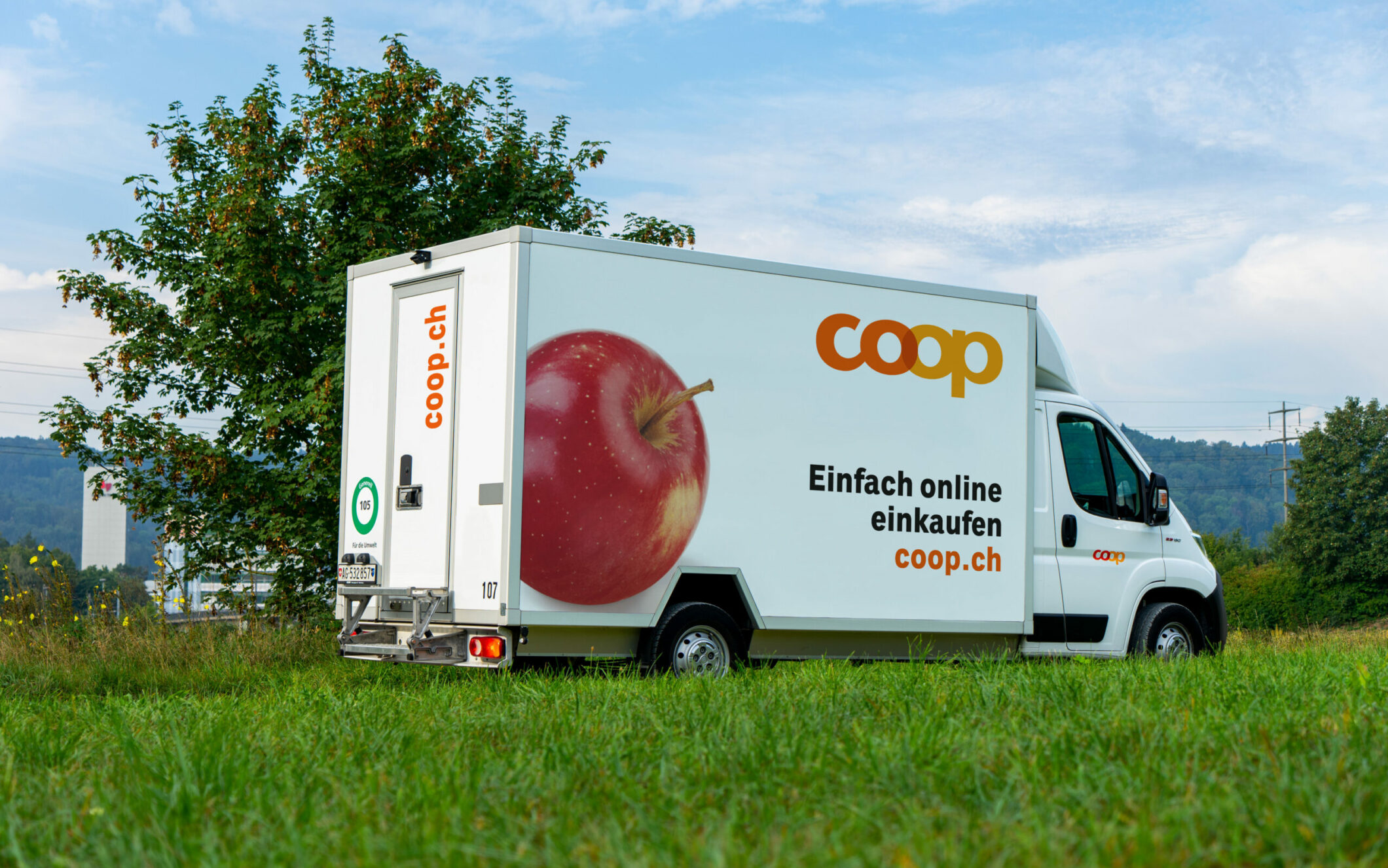 Bild von einem Lieferwagen der auf einer Grünfläche geparkt steht und mit dem Coop Logo gebrandet ist, Omnichannel Plattform