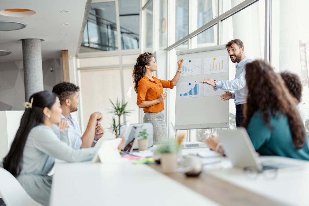 Team diskutiert Statistiken an einem Whiteboard im Büro