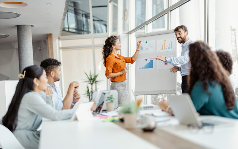 Team diskutiert Statistiken an einem Whiteboard im Büro