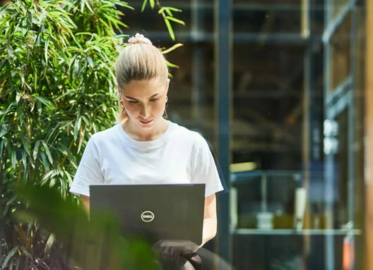 valantic Mitarbeiterin sitzt draußen an ihrem Laptop und arbeitet
