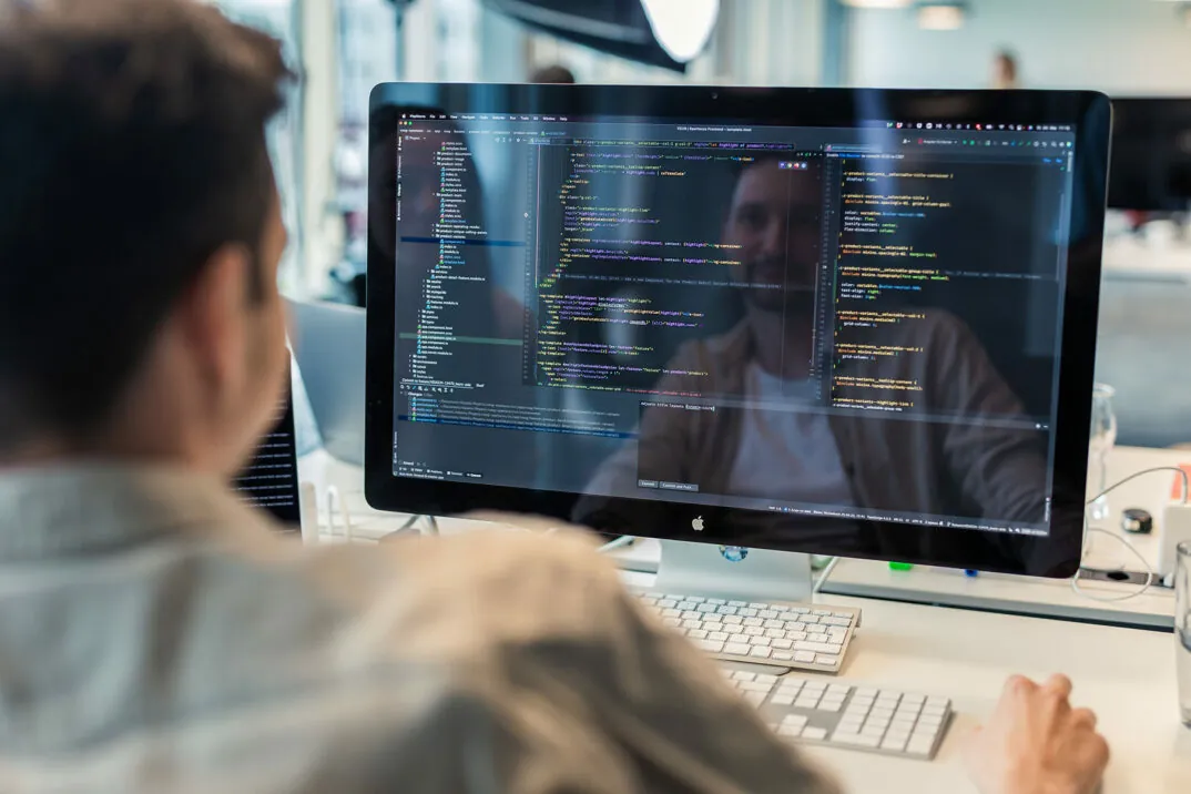Mitarbeiter sitzt am Desktop und codiert