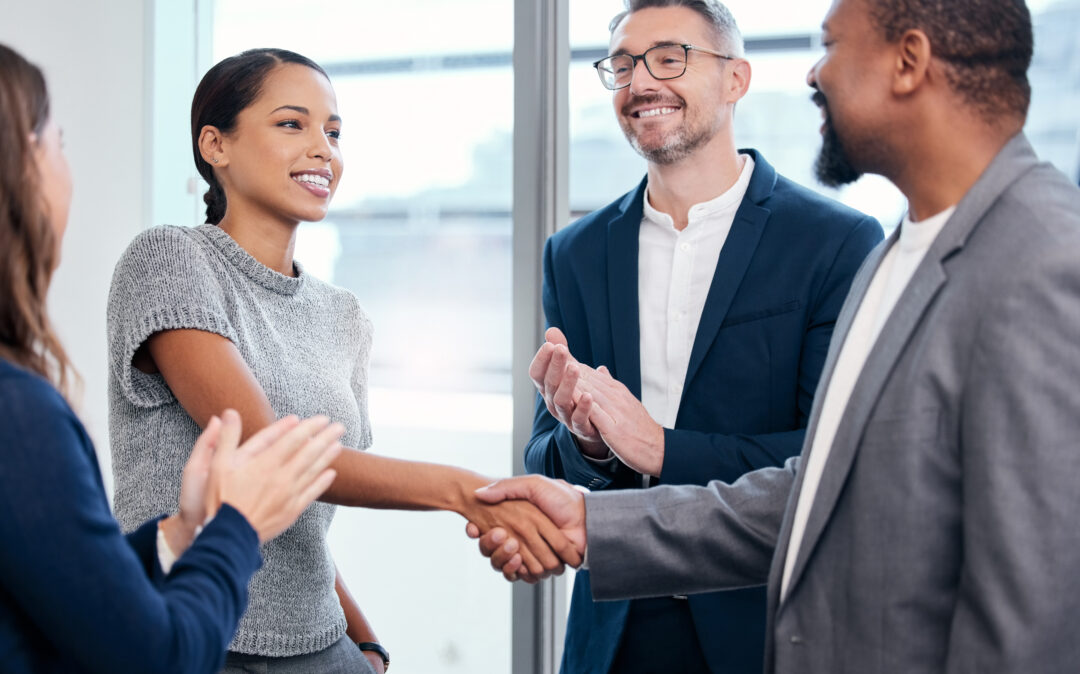 Picture of handshake between woman and man, people applauding around them