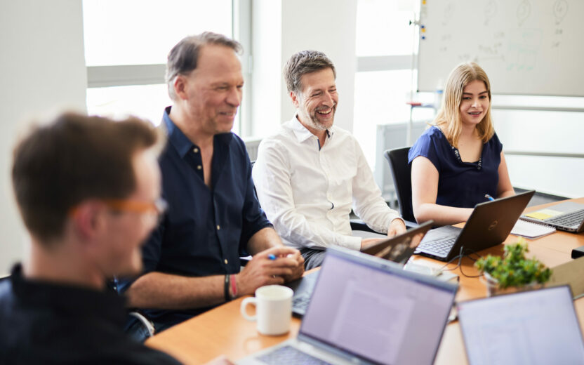 Eine Gruppe Kolleg*innen, die Spaß in einem Meeting haben.