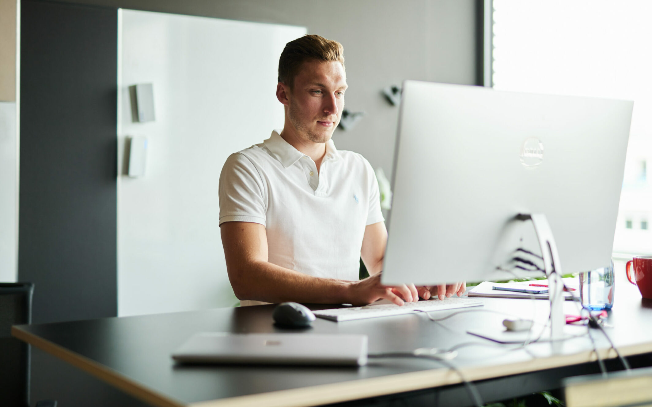 Bild von einem jungen Mann, der konzentriert an einem Stehtisch arbeitet.