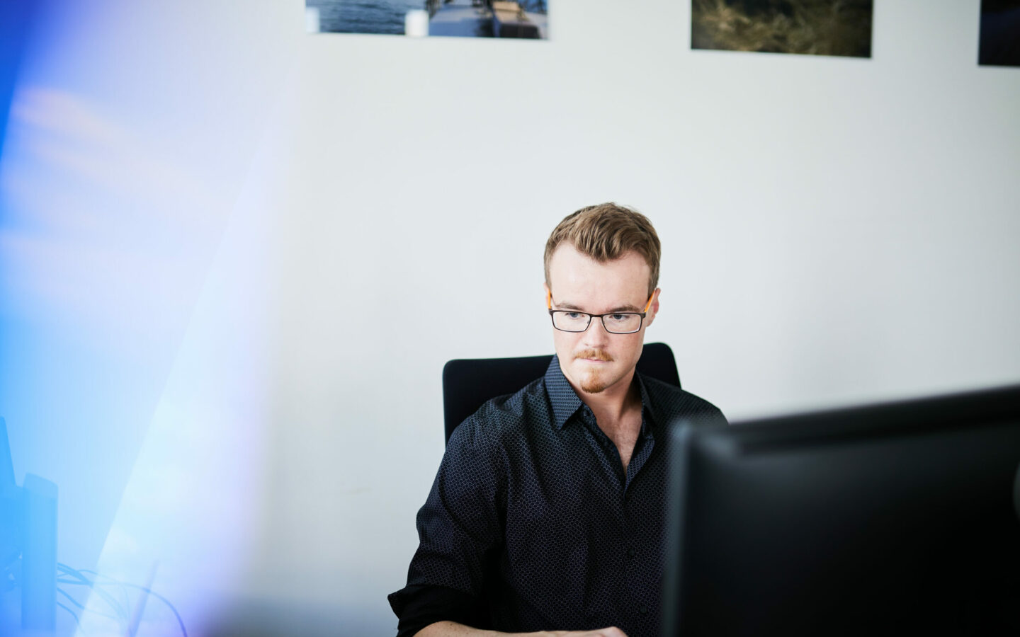 Bild von einem jungen Mann, der vor seinem Computer sitzt und an einer CX-Wesbite-Strategie arbeitet.